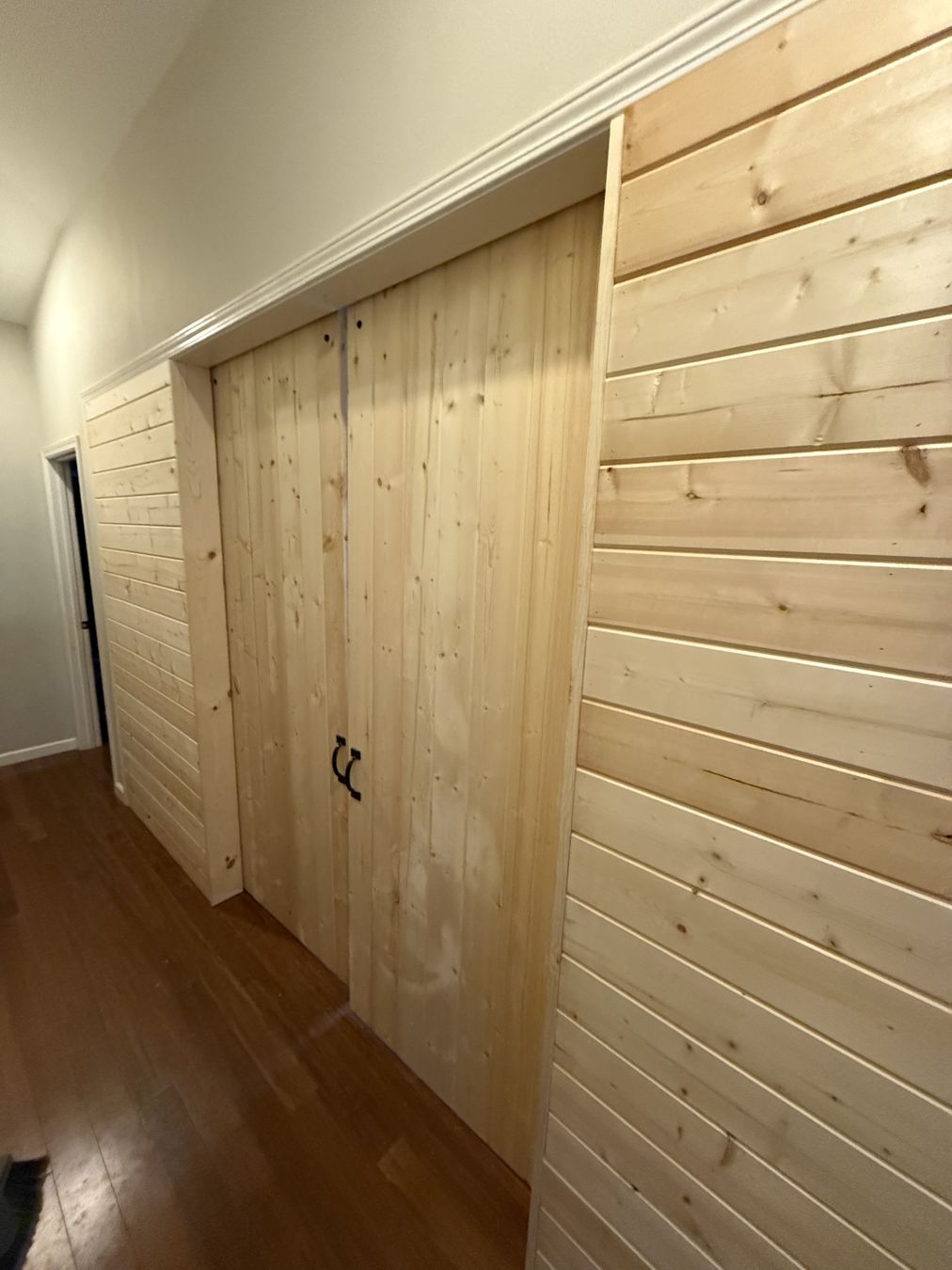 Sliding barn doors with black hardware on a pine plank wall
